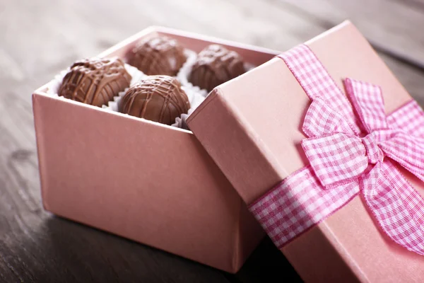 Savoureux bonbons au chocolat en boîte cadeau rose sur fond en bois, gros plan — Photo