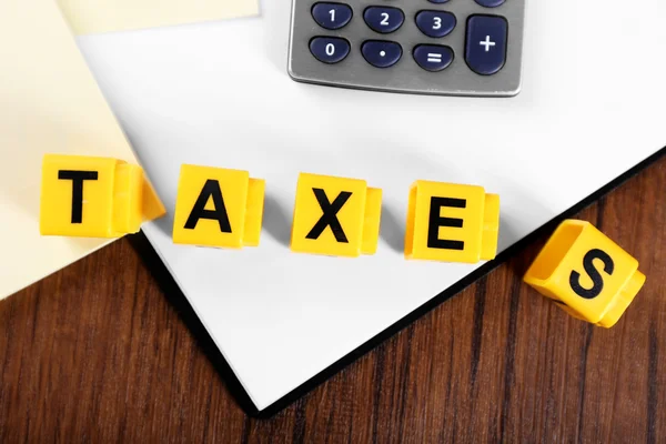 Алфавитные налоги и калькулятор с бумагами на деревянном столе — стоковое фото