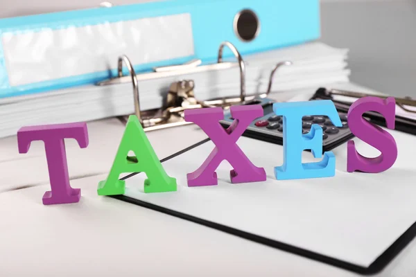Alfabe vergi hesap makinesi ve kağıtları ile tablo — Stok fotoğraf
