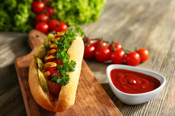 Finom hot-dog, paradicsommal, és ketchup a fa vágódeszka — Stock Fotó