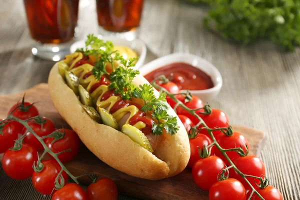Délicieux hot-dog aux tomates et ketchup sur planche à découper en bois, fermer — Photo