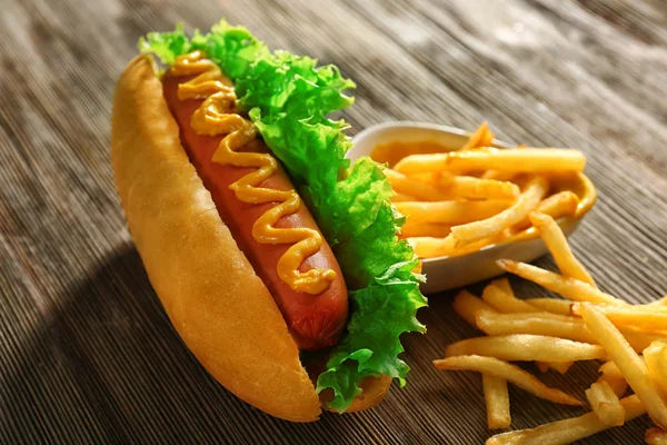 Finom hot-dog, sült krumplival és zöldséggel fából készült háttér — Stock Fotó