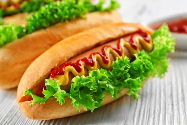 Ízletes hot-dog, fehér fa háttér — Stock Fotó