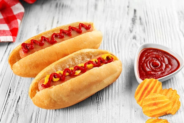 Deliciosos hot-dogs con patatas fritas sobre fondo de madera blanca — Foto de Stock