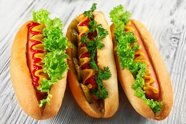 Deliciosos hot-dogs sobre fondo de madera blanca, de cerca —  Fotos de Stock