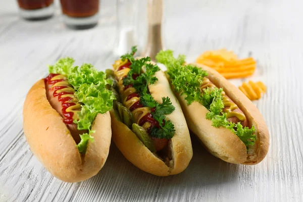 Délicieux hot-dogs avec des chips sur fond de bois blanc, gros plan — Photo