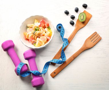 Meyve salatası ve ahşap arka plan üzerinde halter. Sağlıklı beslenme kavramı. 