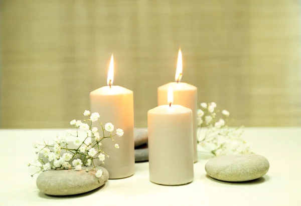 Beautiful composition of alight candles with pebbles and flowers on the table — Stock Photo, Image