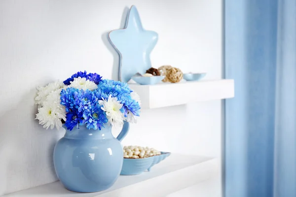 Банка с цветами с голубым декором на полках в номере — стоковое фото