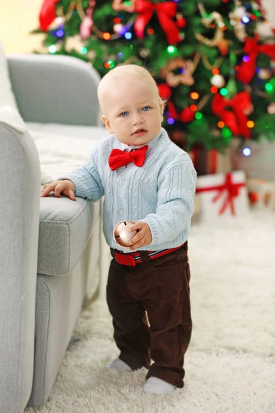 Bebé divertido en el árbol de Navidad en el fondo — Foto de Stock