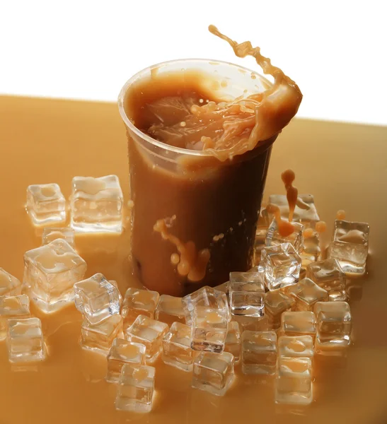 Cup of ice coffee with splashes on table — Stock Photo, Image