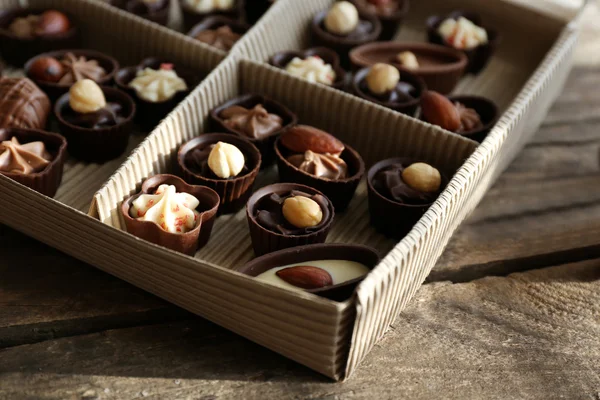 Verschiedene Schokoladenbonbons in Pappschachtel auf Holzgrund, Nahaufnahme — Stockfoto