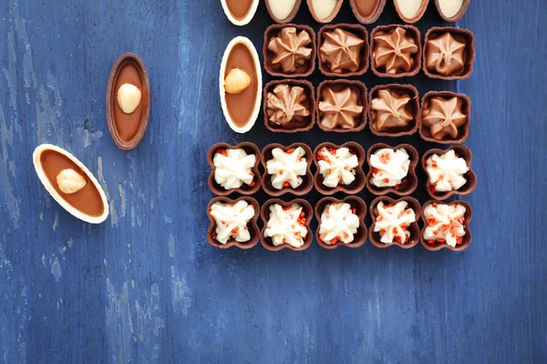 Heerlijke chocolade snoepjes op blauwe houten achtergrond — Stockfoto