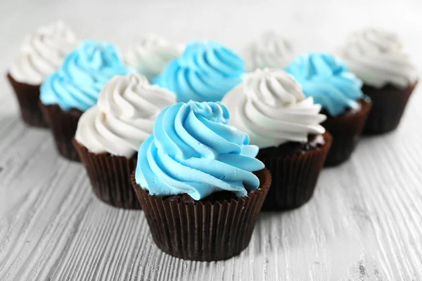 Frische leckere Cupcakes in einer Reihe auf weißem Holzhintergrund — Stockfoto