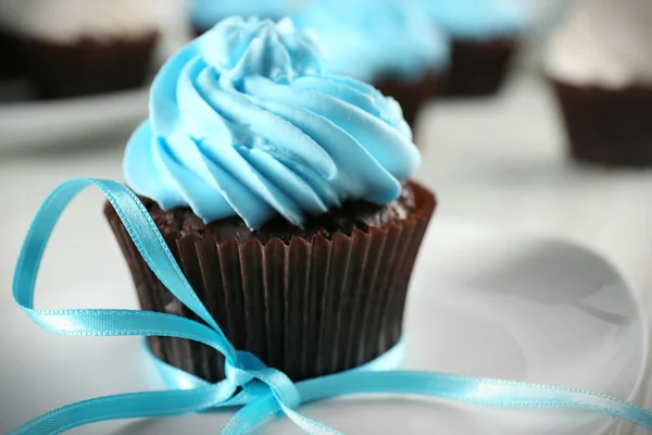 Pyszne czekoladowe ciastko z niebieski krem na urządzony drewniany stół, z bliska — Zdjęcie stockowe
