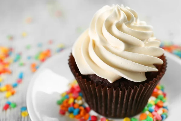 Delicious chocolate cupcake decorated with colourful confectionery on served table, close up — Stock Photo, Image