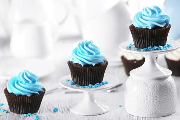 Deliciosos cupcakes de chocolate com creme azul em uma fileira na mesa de madeira decorada, close-up — Fotografia de Stock