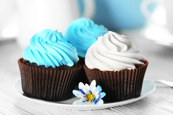 Magdalenas de chocolate con crema de colores en platillo blanco, de cerca — Foto de Stock