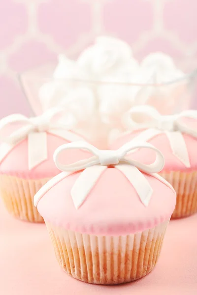 Sabroso cupcake con arco y zapatos de bebé, chupete sobre fondo de color — Foto de Stock