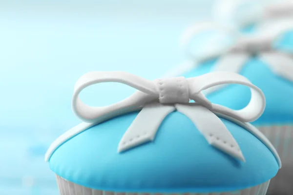 Sabrosos cupcakes con lazo sobre fondo de madera de color — Foto de Stock