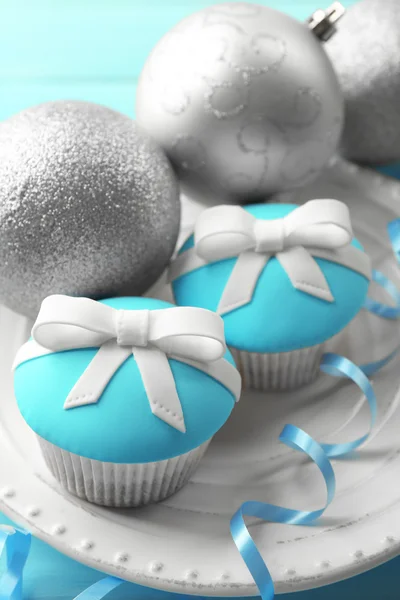 Mumsiga muffins med båge och jul leksaker på färg trä bakgrund — Stockfoto