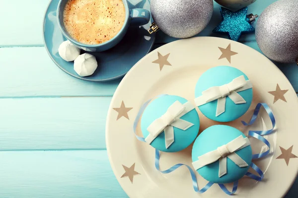 Leckere Cupcakes mit Schleife, Kaffeetasse und Weihnachtsspielzeug auf farbigem Holzhintergrund — Stockfoto