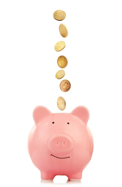 Pink piggy bank with coins falling into slot — Stock Photo, Image