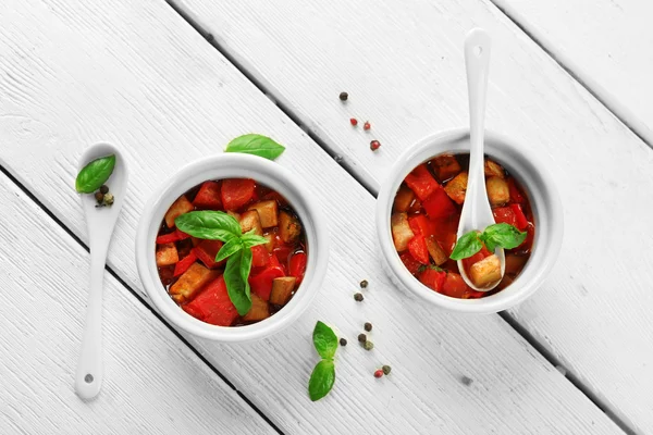 Smakelijke vegetarische ratatouille gemaakt van aubergines, squash, tomaten in kommen op houten tafel achtergrond — Stockfoto