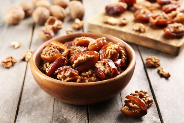 Walnut and date fruit in bowl on wooden table, close-up — Stock Photo, Image