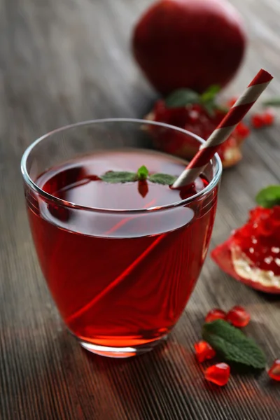 Un verre de jus savoureux et de fruits grenat, sur fond de bois — Photo