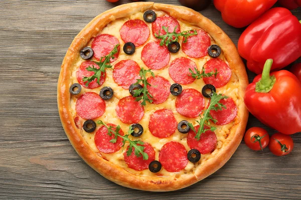 Pizza saporita con salame e verdure rosse su fondo di legno, primo piano — Foto Stock