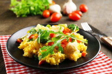 Hizmet ahşap masa üzerinde sebze risotto ile siyah plaka