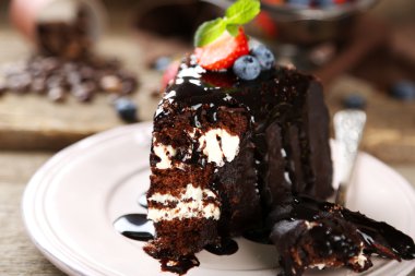 Ahşap arka plan üzerinde plaka üzerinde krem ve taze çilek ile çikolatalı kek