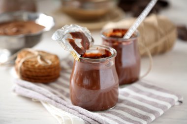 Ahşap arka plan üzerinde çikolata tatlı küçük bir cam kavanozlar