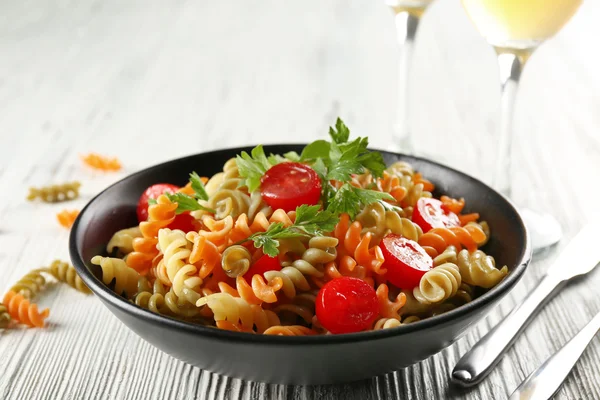 Delicioso plato de macarrones en tazón negro sobre mesa de madera gris servida — Foto de Stock