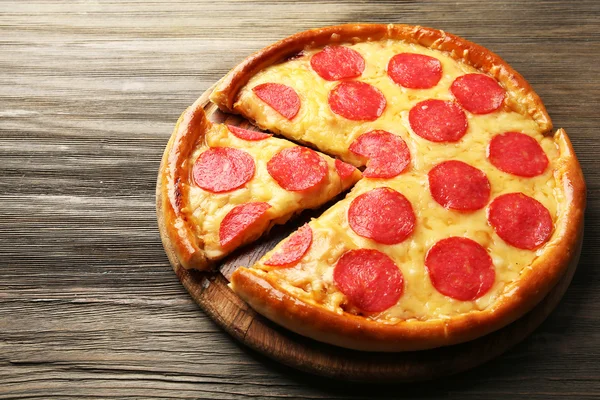 Pizza gostosa quente com salame em fundo de madeira — Fotografia de Stock