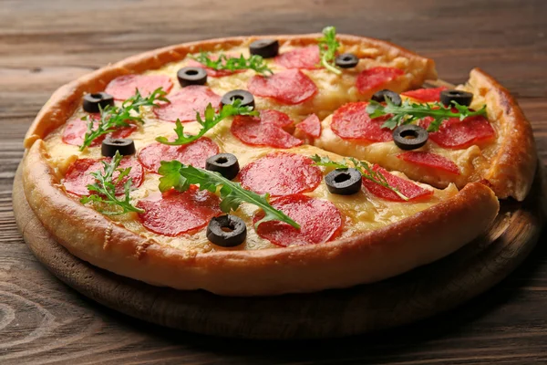 Gorący smaczne pizza z salami i oliwki na drewniane tła — Zdjęcie stockowe