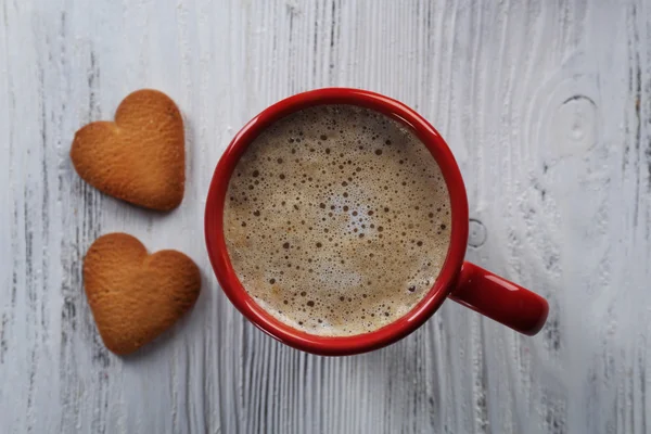 Tazza rossa di cacao caldo e biscotti a forma di cuore su sfondo di legno — Foto Stock