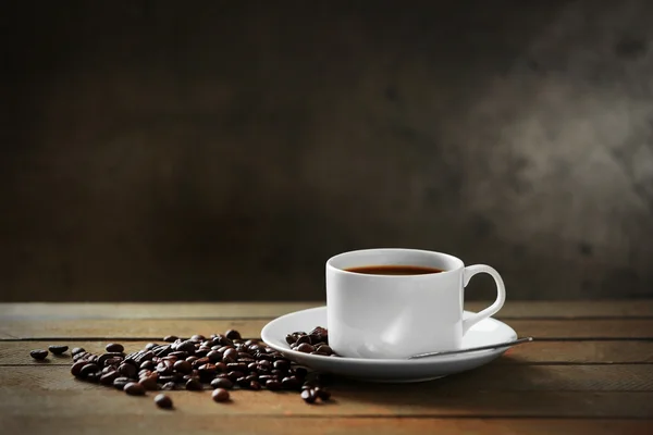 Copa de granos de café y café sobre mesa de madera, sobre fondo gris — Foto de Stock