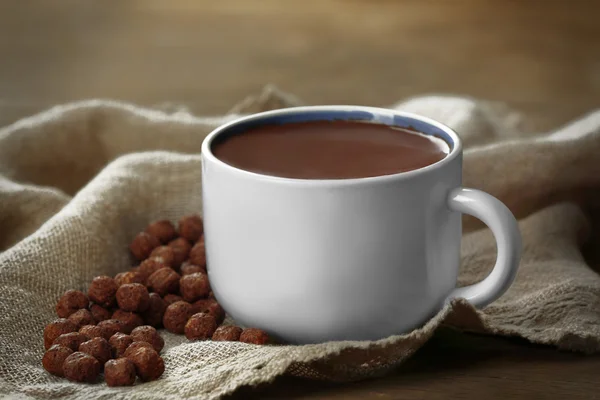 Cup of cacao with sweets and napkin on wooden table