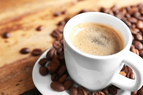Xícara de grãos de café e café em fundo de mesa de madeira — Fotografia de Stock