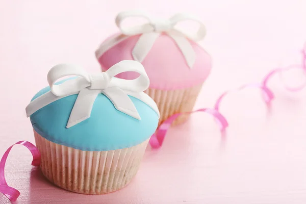 Leckere Cupcakes mit Schleife auf farbigem Holzhintergrund — Stockfoto