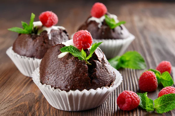 Leckere Schokoladen-Cupcakes mit Beeren und frischer Minze auf Holztisch aus nächster Nähe — Stockfoto