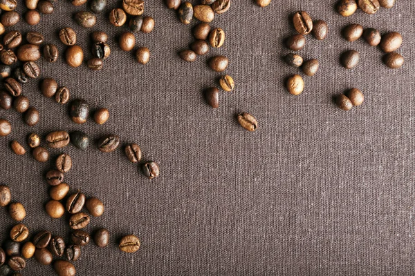 Roasted coffee beans on grey textile background — Stock Photo, Image