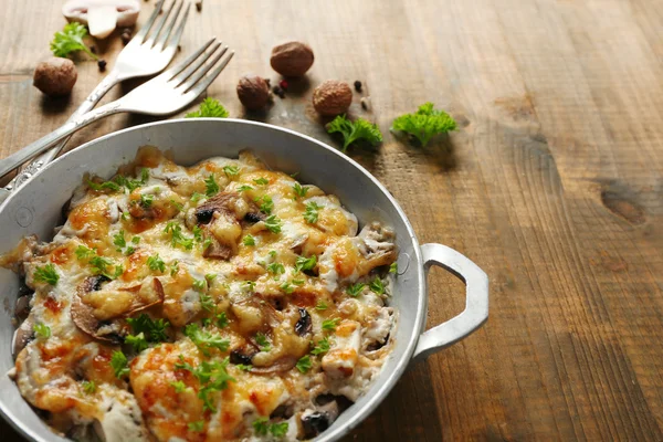 Roasted mushrooms, chicken and cheese gratin in pan, on wooden background — Stock Photo, Image