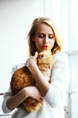 kadın kırmızı kedi elinde tutar.