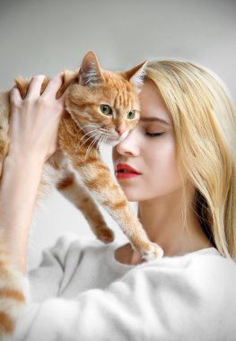 kadın kırmızı kedi elinde tutar.