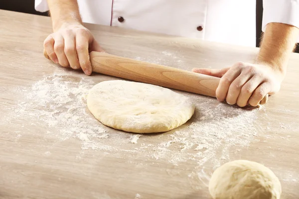 Руки катятся тесто для пиццы на деревянном столе, крупным планом — стоковое фото