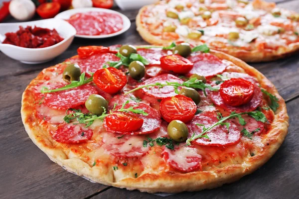 Heerlijke smakelijke pizza's met ingrediënten op tafel, close-up — Stockfoto