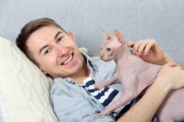 Yakışıklı adam ile kedi kanepede yatıyor